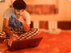 Abhishek as a student, cross-legged on the floor, working on a laptop